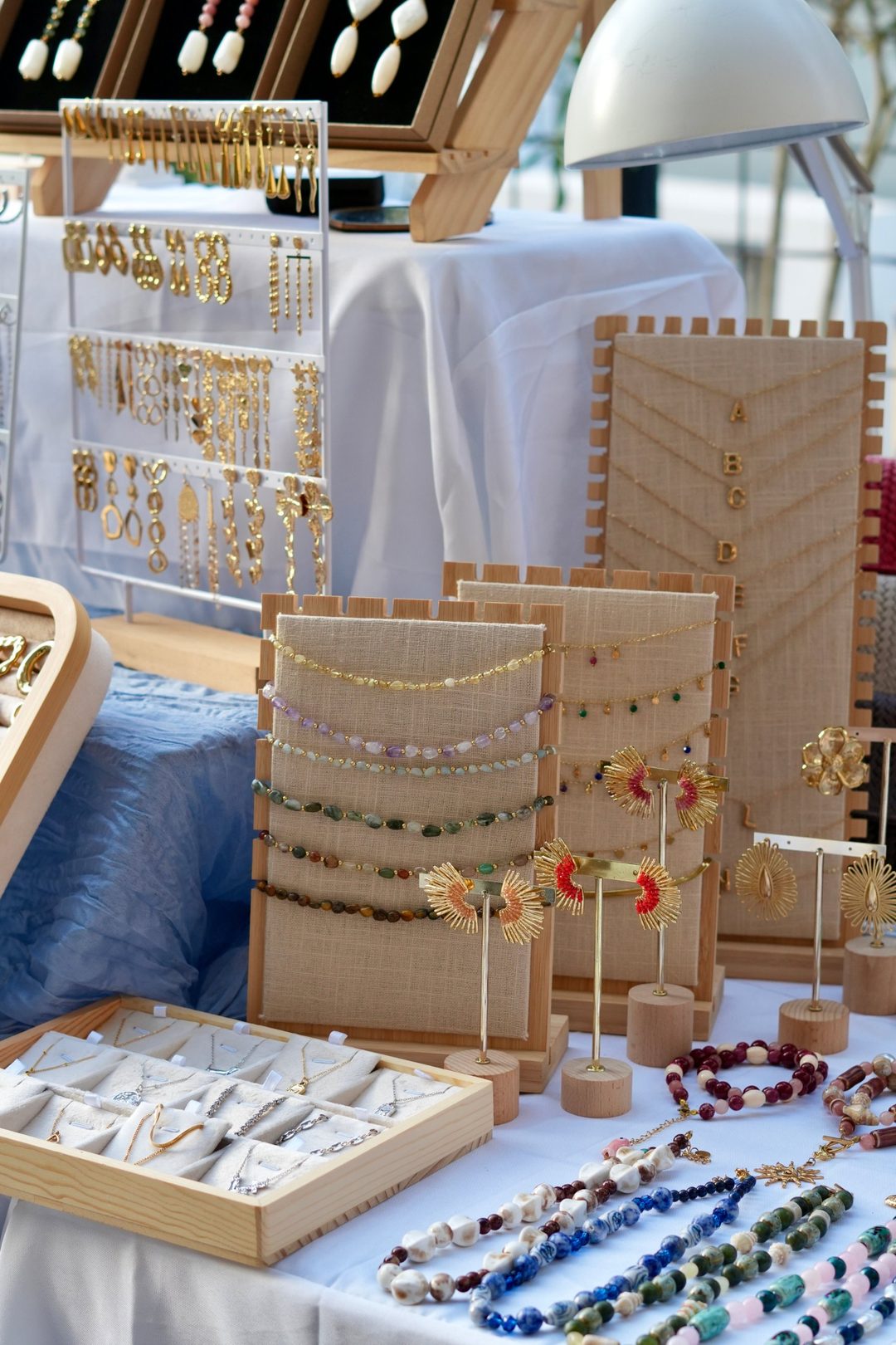 Stand de joyería en Noniná Market con collares, pendientes dorados y expositores de madera